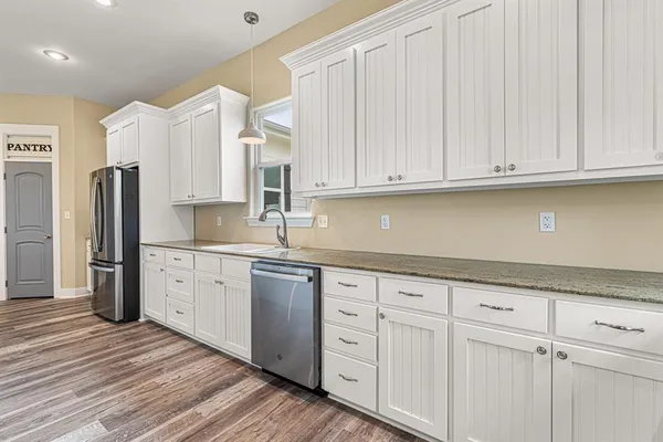 a kitchen with granite countertop white cabinets and stainless steel appliances