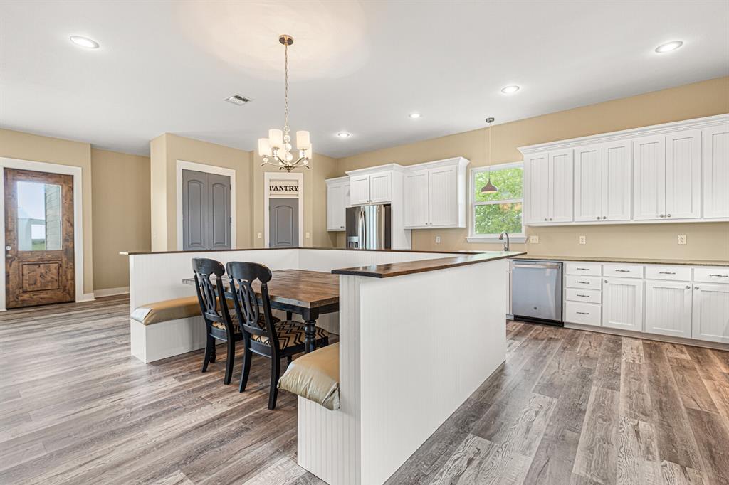 10160 Wallace Road Holland, TX 76534 - Photo 30 of 40 Kitchen featuring appliances with stainless steel finishes, hanging light fixtures, a kitchen breakfast bar, white cabinetry, and light wood-style floors