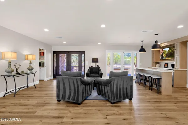 a living room with furniture a flat screen tv and a refrigerator
