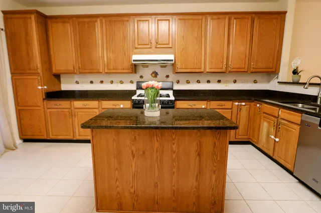 a kitchen with granite countertop a sink a stove and cabinets