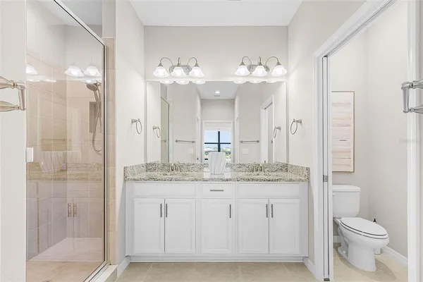 a bathroom with a granite countertop sink a toilet and a mirror