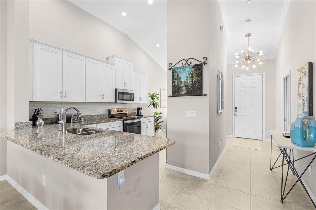13725 Messina Loop, Unit 201 Bradenton, FL 34211 - Photo 5 of 39 a kitchen with stainless steel appliances granite countertop a sink dishwasher and a refrigerator with wooden floor