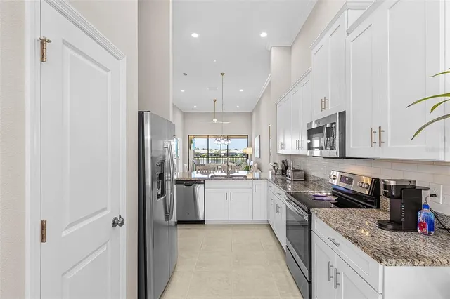 a large kitchen with stainless steel appliances granite countertop a stove refrigerator and cabinets