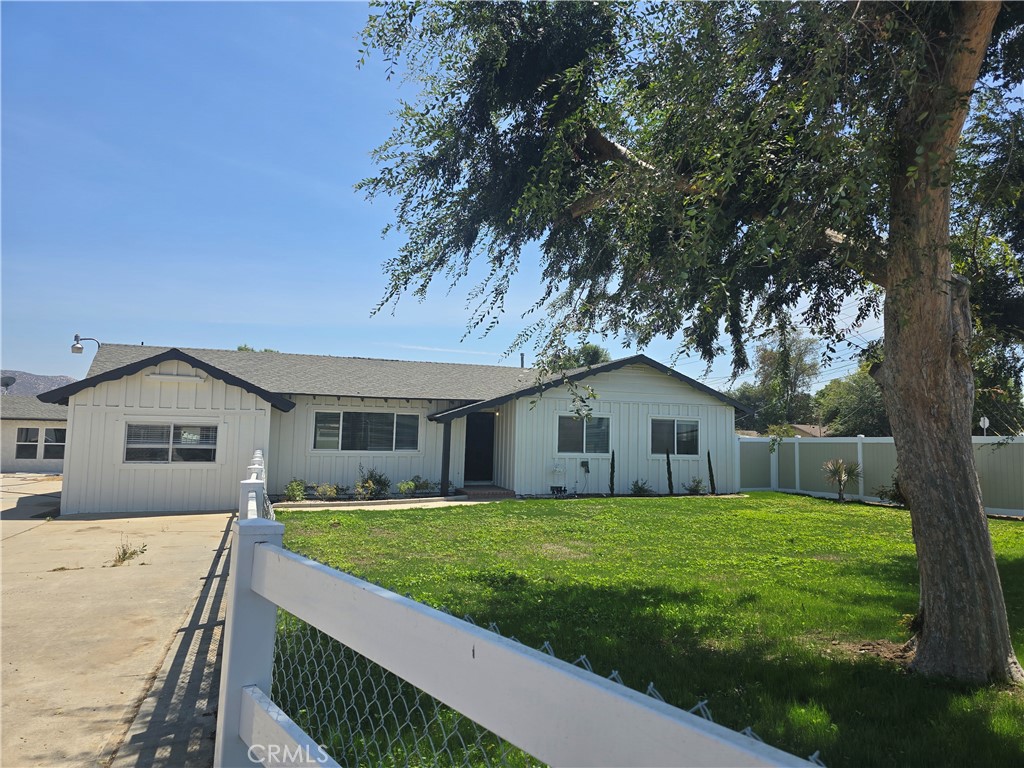 a view of house with a big yard and large trees