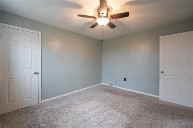 an empty room with chandelier fan