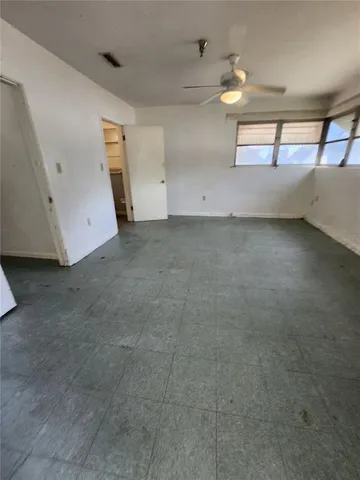 an empty room with a ceiling fan and carpet