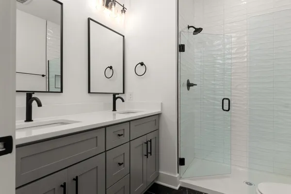 a bathroom with a double vanity sink mirror and shower