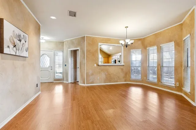 an empty room with wooden floor and large windows