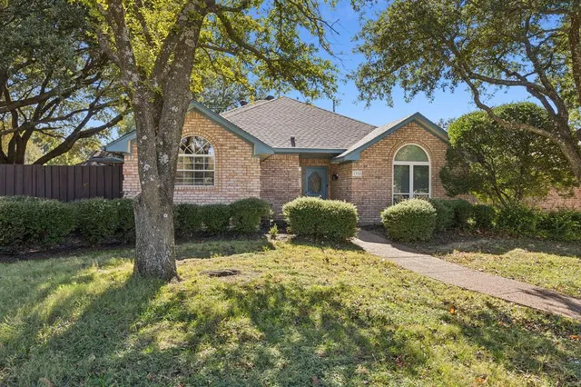 a front view of a house with a yard and large tree