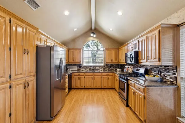 a kitchen with stainless steel appliances granite countertop a stove a sink dishwasher a refrigerator and a stove with wooden floors