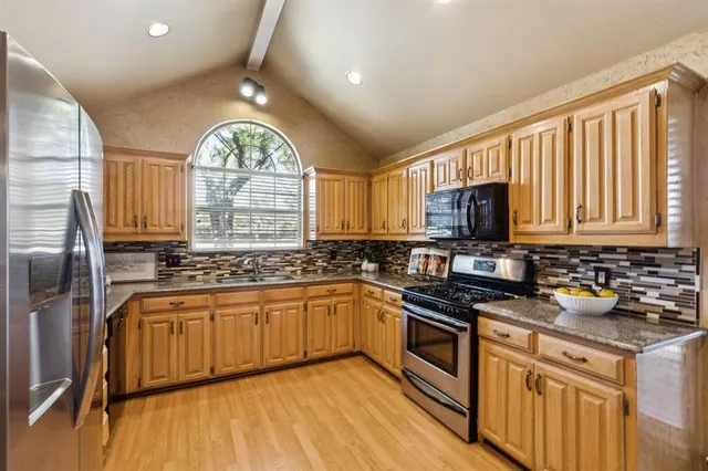 a kitchen with stainless steel appliances granite countertop a stove a sink dishwasher and a microwave oven with wooden floor