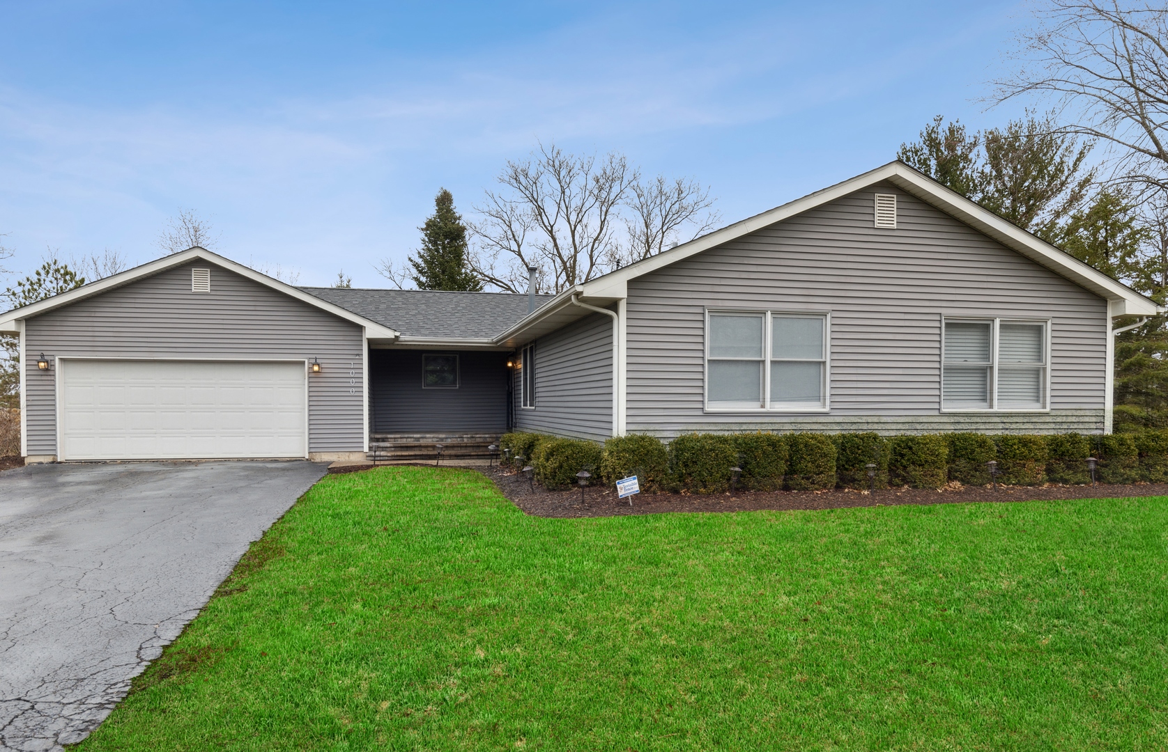 a front view of a house with a garden and yard