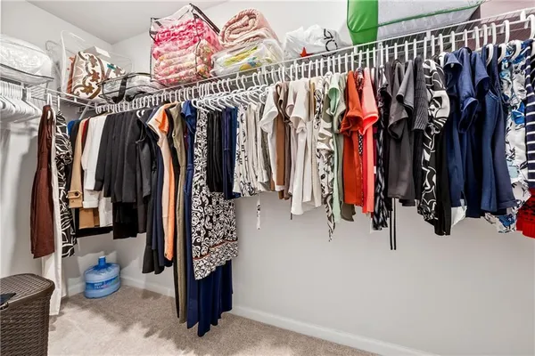 a view of walk in closet with clothes and shoes