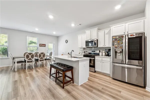 a kitchen with stainless steel appliances granite countertop a stove refrigerator and a dining table with wooden floor