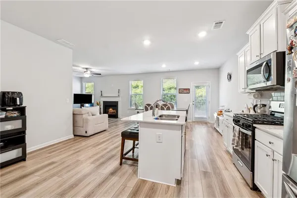 a living room with furniture a fireplace a flat screen tv and kitchen view