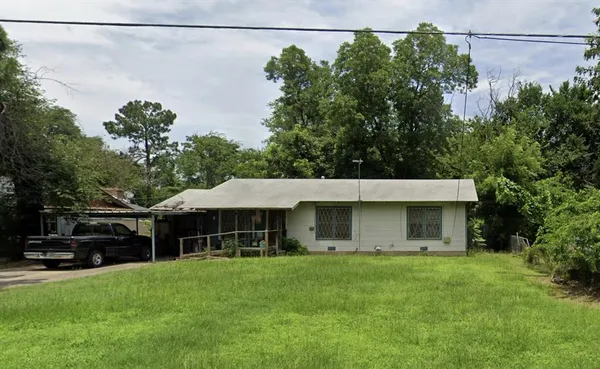 a front view of a house with a garden and trees