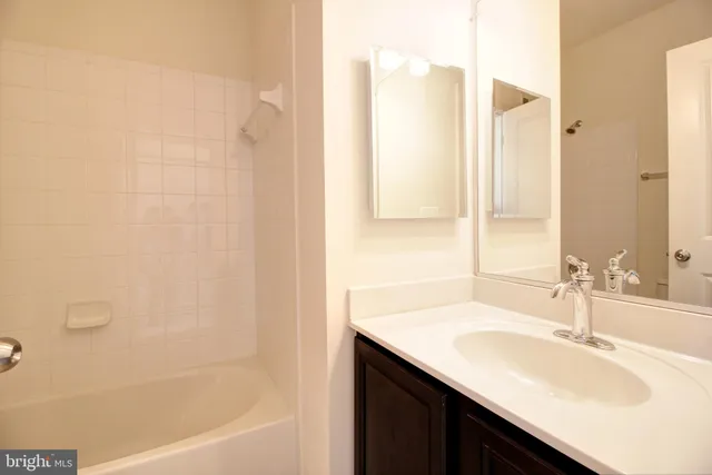 a bathroom with a granite countertop sink and a bathtub