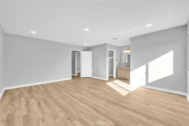 a view of an empty room with wooden floor and windows