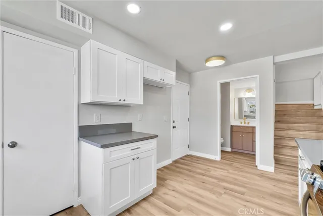a kitchen with white cabinets and sink
