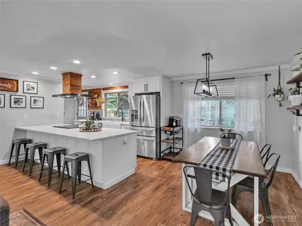 a kitchen with stainless steel appliances a dining table chairs and wooden floor
