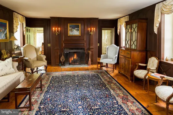 a view of a hallway with wooden floor and a livingroom with furniture