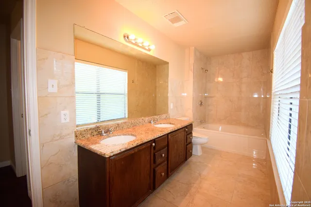 a bathroom with a granite countertop sink and a bathtub