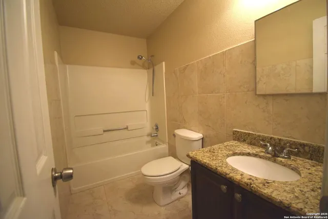 a bathroom with a granite countertop sink toilet and shower