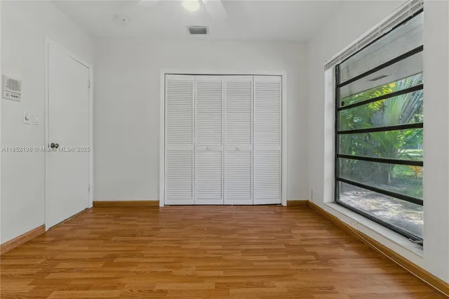 a view of empty room with wooden floor and fan