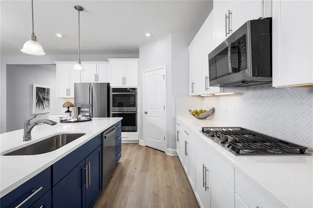 a kitchen with stainless steel appliances a sink a stove oven a refrigerator with cabinets and wooden floor