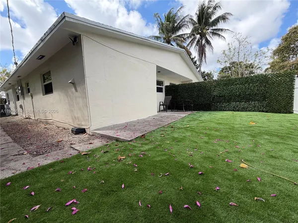 a backyard of a house with potted plants and palm trees