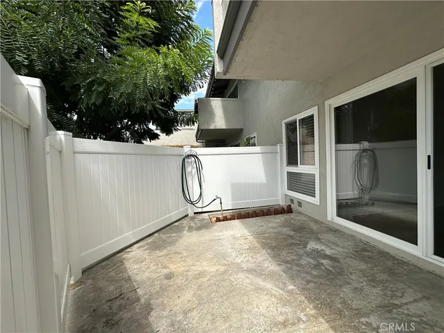 a view of a patio with couches table and chairs with plants and wooden fence