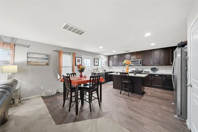a kitchen with stainless steel appliances kitchen island granite countertop a table chairs sink and cabinets
