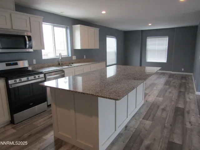 a kitchen with granite countertop a stove a sink and a microwave