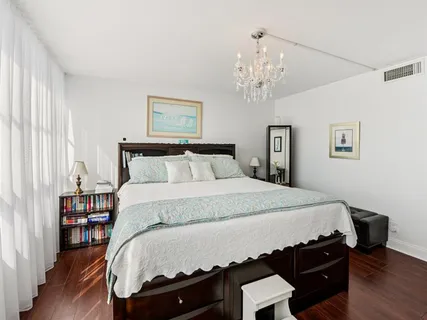 a bedroom with a bed a dresser and wooden floor