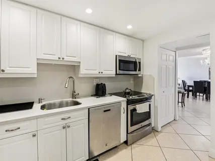 a kitchen with granite countertop white cabinets and stainless steel appliances