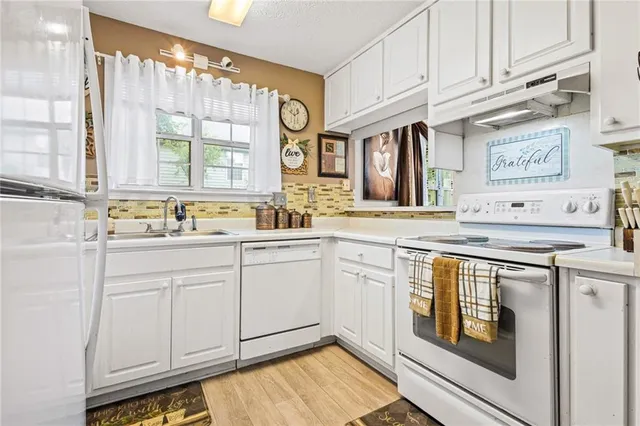 a kitchen with granite countertop white cabinets and white appliances
