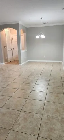 an empty room with kitchen and chandelier fan