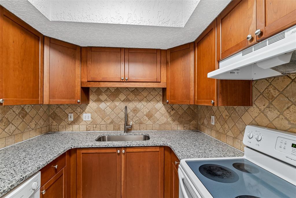 263 14th Street Northwest, Unit 3A Largo, FL 33770 - Photo 5 of 11 a kitchen with a sink a stove top oven a counter space and cabinets