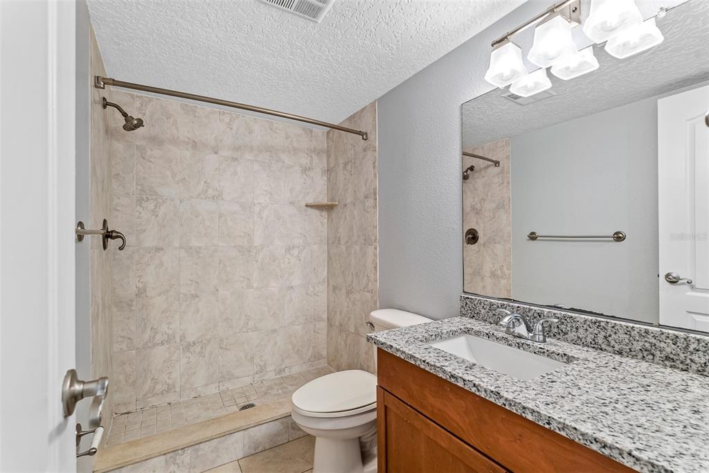 263 14th Street Northwest, Unit 3A Largo, FL 33770 - Photo 7 of 11 a bathroom with a granite countertop sink a toilet and shower