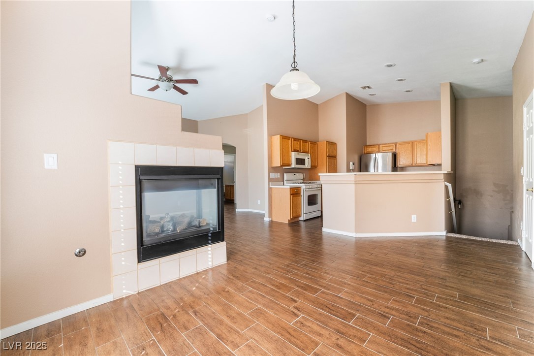 1570 Rusty Ridge Lane Henderson, NV 89002 - Photo 8 of 35 Unfurnished living room with high vaulted ceiling, baseboards, wood finished floors, and ceiling fan