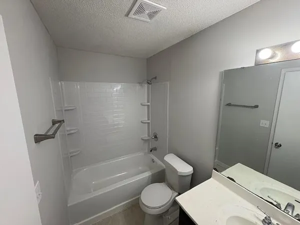 a bathroom with a granite countertop toilet a sink and a bathtub