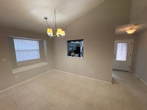 an empty room with chandelier fan and windows