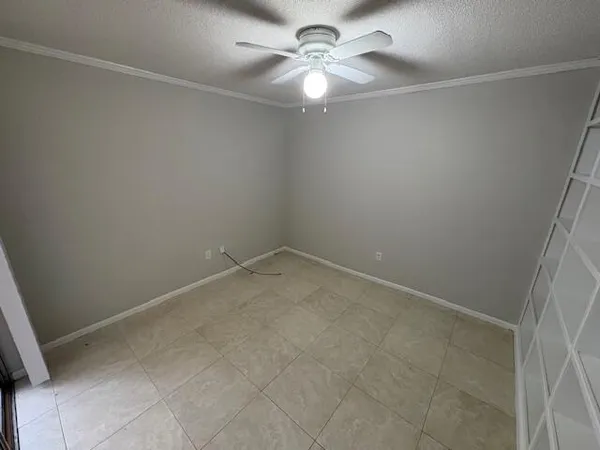 an empty room with a fan & a window