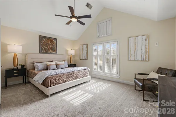 a spacious bedroom with a bed a chandelier and a window