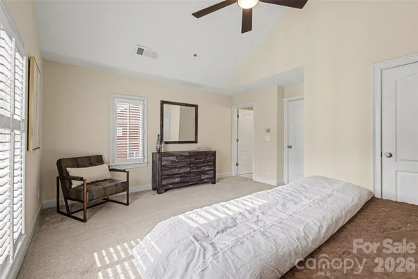 a spacious bedroom with a bed a chandelier and a couch