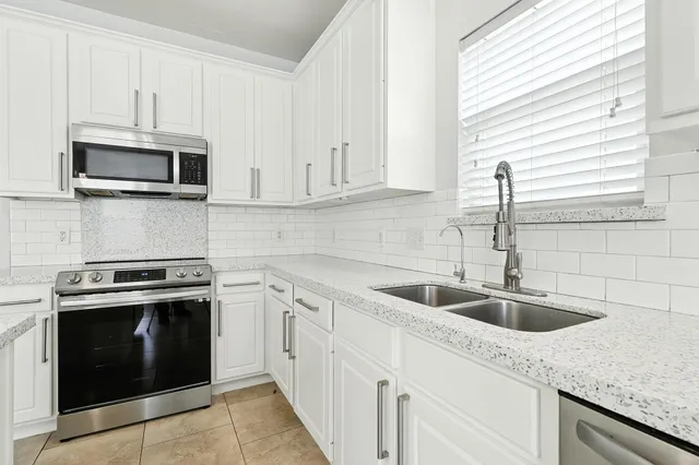 a kitchen with white cabinets sink and stainless steel appliances