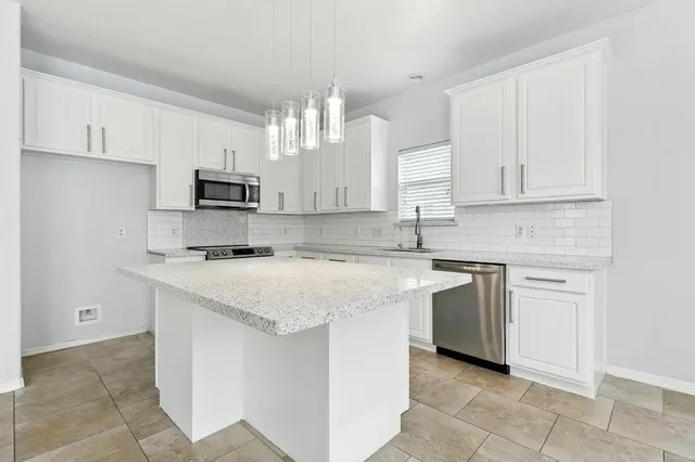 a kitchen with kitchen island granite countertop a sink a counter top space and cabinets