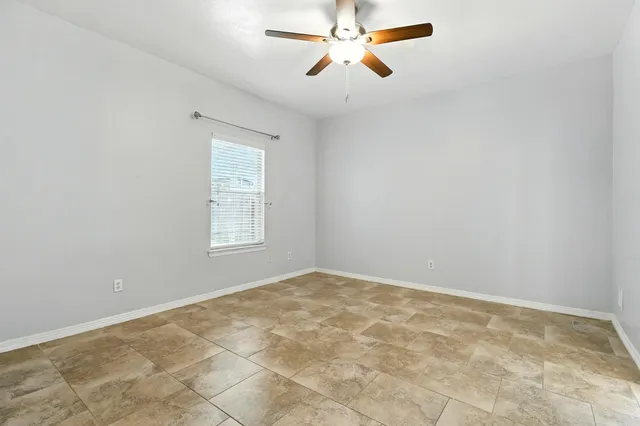 an empty room with windows and fan