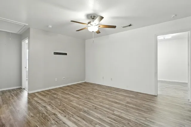 a view of a room with wooden floor and a ceiling fan