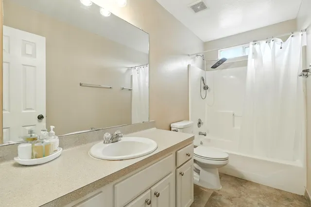a bathroom with a granite countertop sink a toilet a mirror and shower
